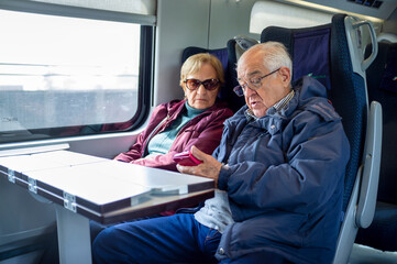 Senior Couple Using Smartphone While Traveling by Train