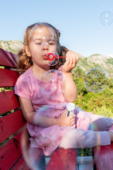 Cute funny little girl toddler child blowing soap bubbles in park summer outside