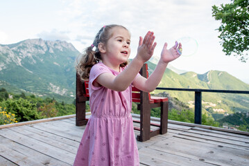 Cute funny little girl toddler child blowing soap bubbles in park summer outside