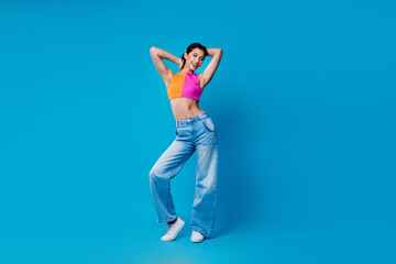 Energetic young woman in vibrant clothing posing confidently smiling and enjoying leisure against a...