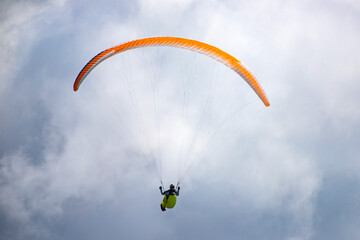 A man with a paraglider in front of a blue sky.