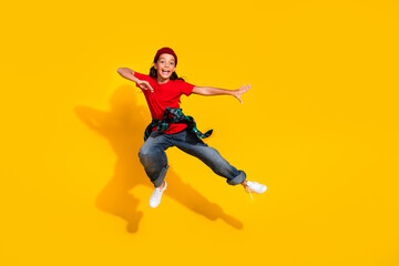 Energetic young girl performing a joyful leap against a vivid yellow background, embodying youthful...