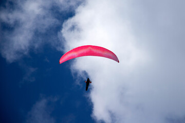 A man with a paraglider in front of a blue sky.