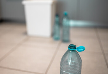Plastic bottles next to a trash bin. Sorting plastic for easier recycling of waste.
