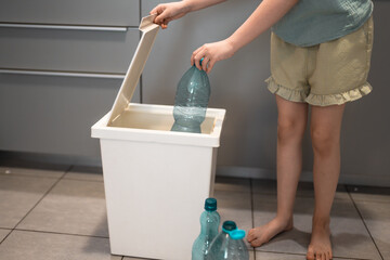Plastic bottles next to a trash bin. Sorting plastic for easier recycling of waste.