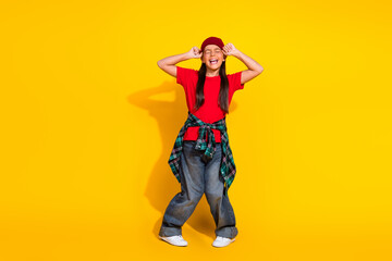 Young girl in casual trendy outfit celebrating enthusiastically against a vibrant yellow background