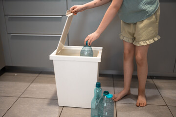 Plastic bottles next to a trash bin. Sorting plastic for easier recycling of waste.