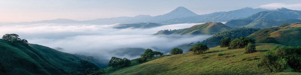 Majestic mountain landscape with rolling hills and misty valley at sunrise