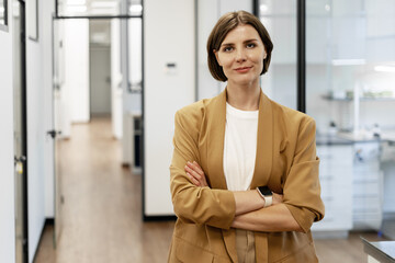 Businesswoman with crossed arms standing in modern office corridor