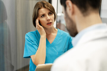 Worried nurse suffering headache talking with doctor about bad news
