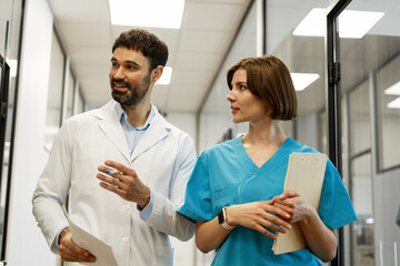 Obraz premium Doctors discussing diagnosis while walking in hospital corridor