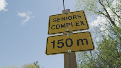 Yellow Seniors Complex Sign on Wooden Post Against Blue Summer Sky – 150 Meters Warning, Georgetown, Ontario, Canada