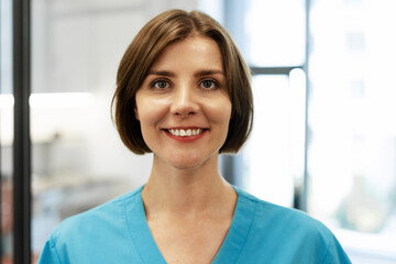 Smiling doctor wearing blue uniform standing in clinic