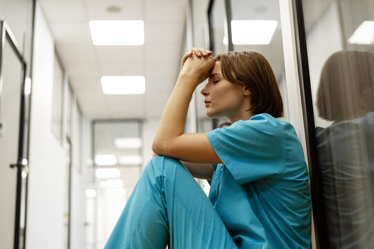 Exhausted doctor sitting on floor in hospital corridor taking a break