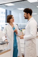 Medical professionals discussing near laboratory equipment in modern clinic