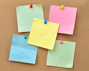 Colorful notes on a cork wall with a pin