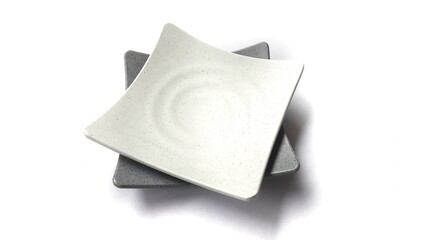 Stack of empty square white and grey plates with ceramic melamin material isolated on white background
