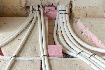 Electricity tubing is laid across the floor of an unfinished room. Construction of electric system