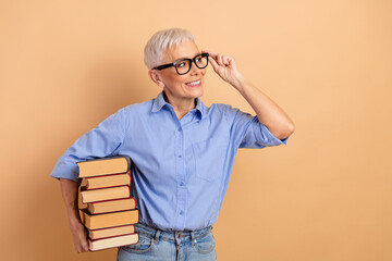 Attractive senior businesswoman with short white hair holds book while smiling against a beige...