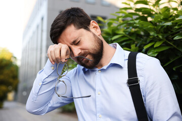 Tired businessman with glasses outside office building