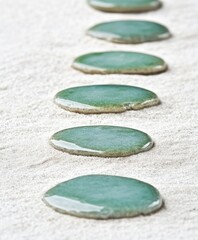 Teal stones in a line on light beige sand