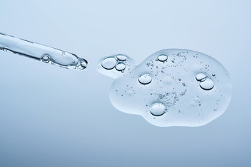 The texture of the facial serum with bubbles and an eyedropper on a blue background.