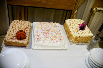 Different types of birthday cakes on the table next to the plates ready to be served
