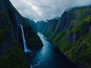 A dramatic aerial scene of a deep Norwegian fjord framed by towering cliffs and lush greenery, with a powerful waterfall cascading into a serene, dark blue river below.

