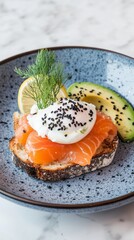 Gourmet breakfast featuring a piece of toasted bread layered with smoked salmon, avocado and creamy poached egg topped with black sesame seeds, served on a blue ceramic rustic style plate