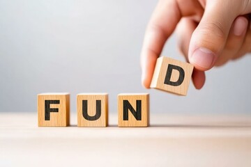 A hand placing the letter D on wooden blocks to complete the word FUND, symbolizing investment, financial growth, and funding opportunities in a minimalistic setting.