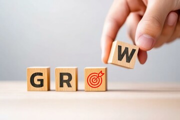 Hand placing the wooden block letter 'W' to form the word 'GROW' on a light wooden surface, symbolizing personal growth and development in business and life.