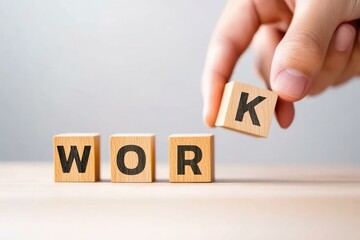 A hand is placing the letter 'K' on wooden blocks that spell out the word ‘WORK', symbolizing focus on professional success and the importance of teamwork in achieving goals.