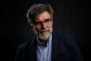 Portrait of handsome man in a studio on a dark background. Handsome man posing. Middle-aged good...