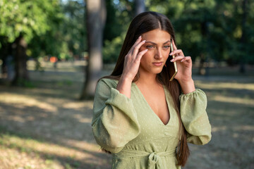Stressed young woman having tense phone call outdoors, negative facial expression reveals emotional...