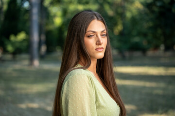 Beautiful young woman portrait outdoors in park, mysterious gaze and thoughtful expression in...