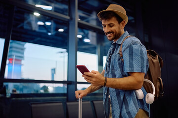 Happy man texting on cell phone before onboarding on a plane.