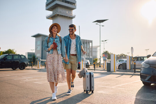 Carefree couple with luggage on parking lot at the airport.