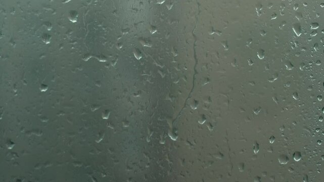 heavy rain outside the window, raindrops pouring down the window glass from the outside, shallow depth of field, concept rainy weather outside the window