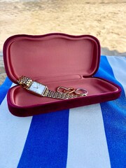 Stylish sunglass case with jewelry on the beach