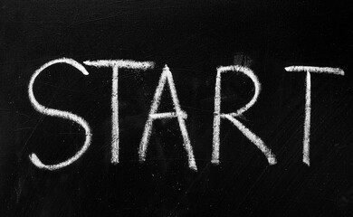 Close-up shot of the word START written in white chalk on a textured black chalkboard, symbolizing new beginnings or a call to action.