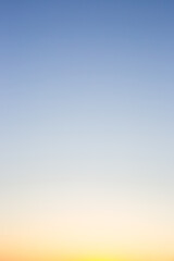A clear, gradient sky transitions from pale blue at the top to soft yellow at the bottom, creating a serene and minimalist backdrop.