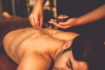 Man customer having exfoliation treatment in luxury spa salon with warmth candle light ambient....