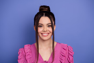 Beautiful young woman in pink ruffled dress against violet background with charming smile and...