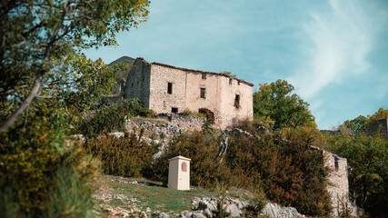  A quiet path leads past a small shrine toward hilltop ruins in the rural countryside of Côte d’Azur, Southern France, photographed in rich autumn light and 4K clarity.