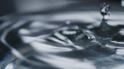 Close-up slow-motion macro shot of liquid medication drop from syringe needle entering glass vial, with ripples, reflections, and crisp micro-particle splashes

 - Powered by Adobe