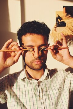 Man crying with pencil sharpener on face in sunset lighting