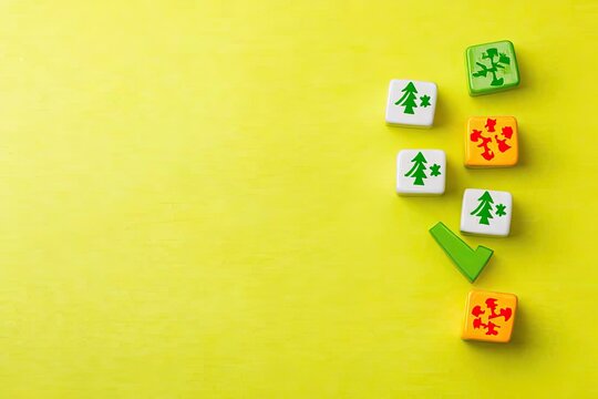 Small, colorful, square blocks with tree and checkmark symbols arranged on a bright yellow background