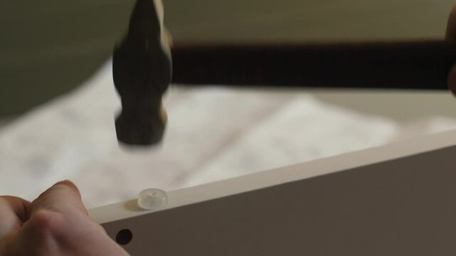 close-up of a carpenter assembling a wooden product, hammering a nail with a rubber cap, a furniture assembler assembling a bed