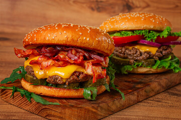 two burgers with beef patty, fried bacon, cheddar cheese, tomatoes, homemade, no people,