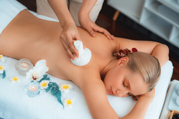 Hot herbal ball spa massage body treatment, masseur gently compresses herb bag on woman body....